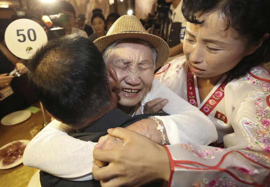 South Korean Lee Keum-seom, center, hugs her North Korean son Ri Sang Chol, who is with daughter-in-law Kim Ok Hui, during the reunion. (Yonhap via AP)