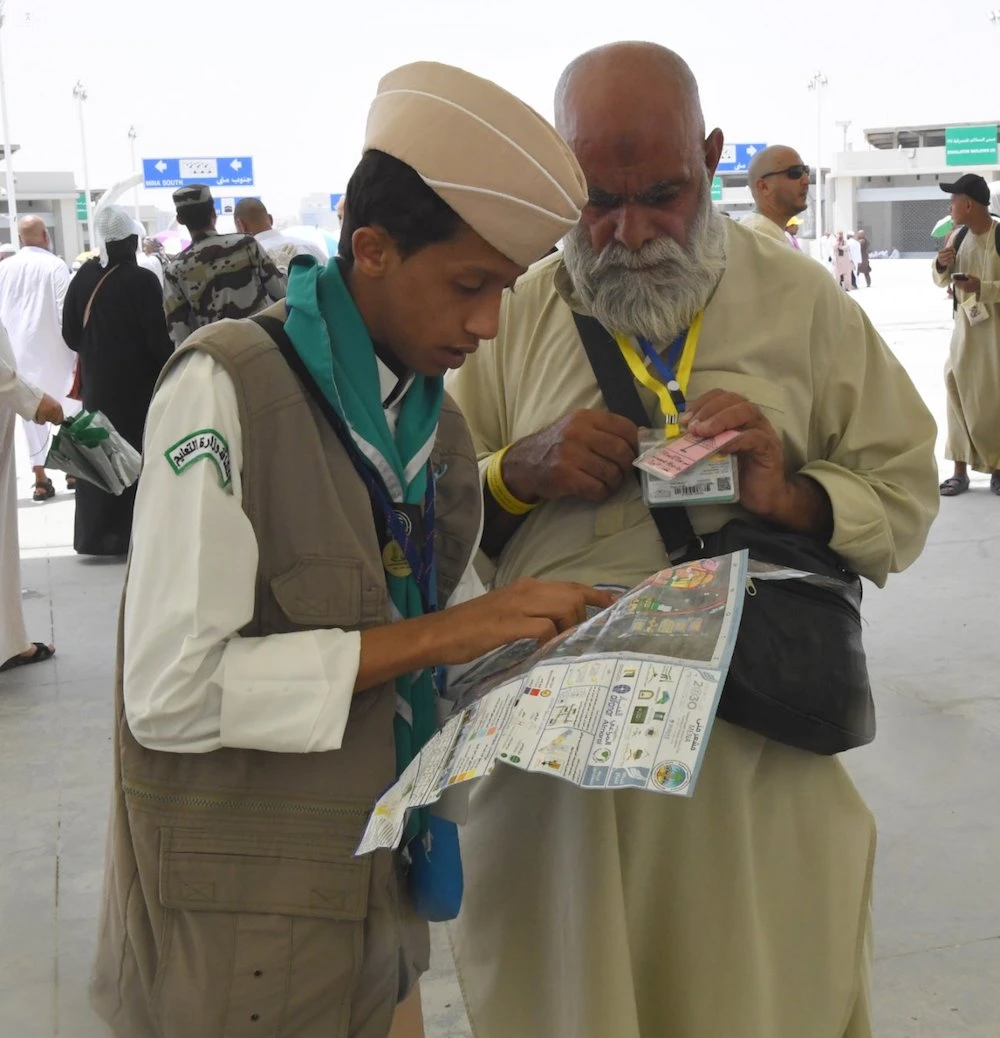 A boy scout assists a pilgrim with directions. (SPA)
