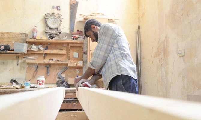 A Syrian furniture worker measures wood at Yussef al-Qabuni's furniture store in the town of Saqba in Damascus eastern Ghouta on August 13, 2018. (AFP)