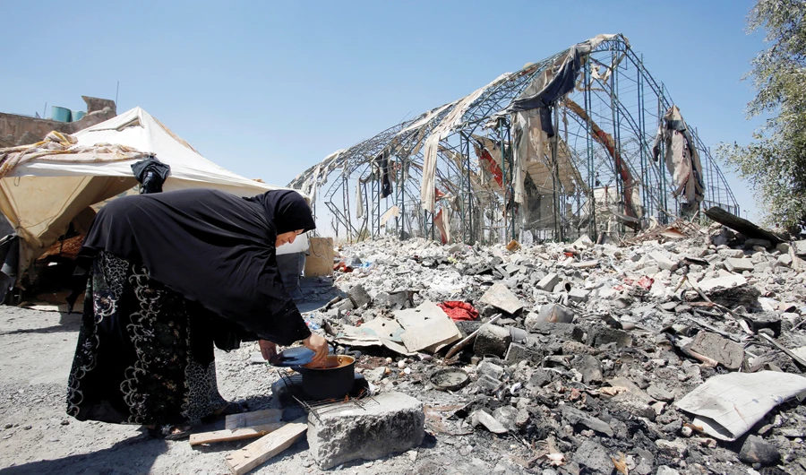 A woman cooks food near a tent where she lives in the old city of Mosul, Iraq. (Reuters)