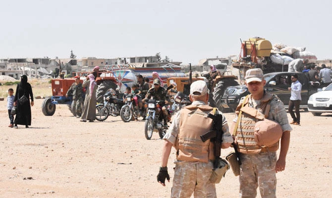 Russian and Syrian forces stand guard as civilians enter the Abu Duhur crossing on the eastern edge of Idlib province on August 20, 2018. (AFP)