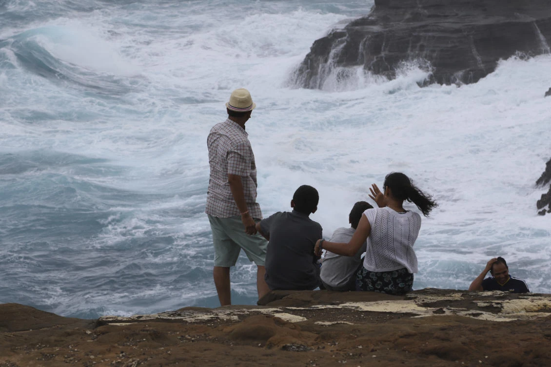 People watch as waves crash along sea cliffs on the southeast shore of Oahu as Hurricane Lane approaches, Friday, Aug. 24, 2018, near Honolulu. (AP)