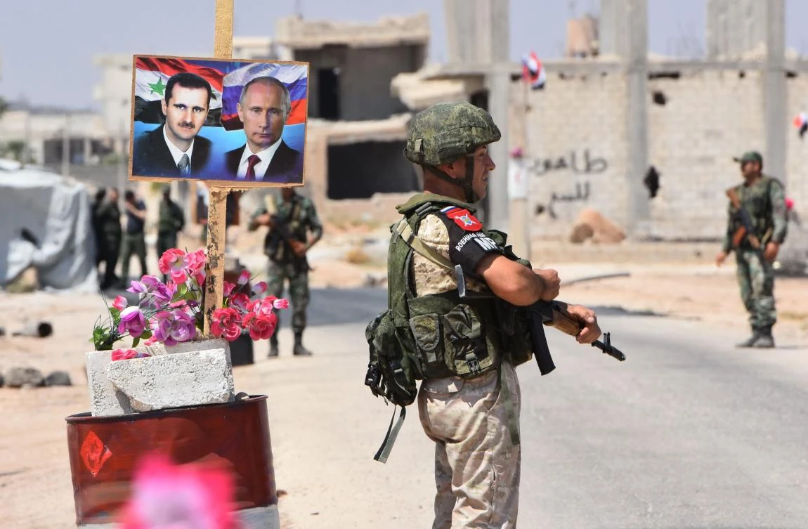 In this file photograph taken on August 20, 2018, members of Russian and Syrian forces stand guard near posters of Syrian President Bashar al-Assad and his Russian counterpart Vladimir Putin at the Abu Duhur crossing on the eastern edge of Idlib province. (AFP)