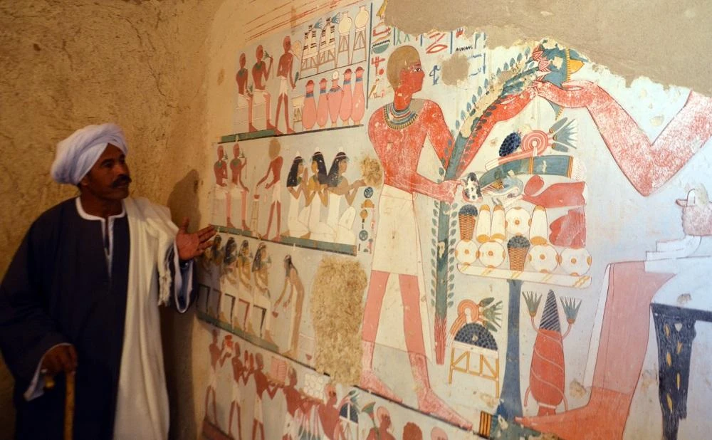 An Egyptian labourer stands next to an ancient Egyptian mural found at the newly discovered "Kampp 161" tomb at Draa Abul Naga necropolis on the west Nile bank of the southern Egyptian city of Luxor. (AFP)