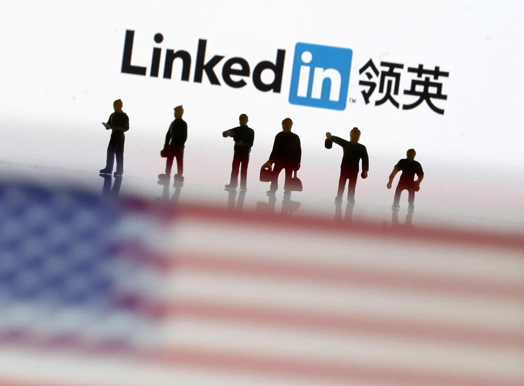 Small toy figures are seen between displayed US flag and Linkedin logo in this illustration picture, August 30, 2018. (Reuters)