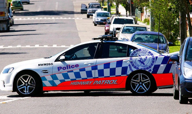 A policeman sits in his patrol car as part of a road block on the street where a house was involved in pre-dawn raids in the western Sydney suburb of Guilford September 18, 2014. (REUTERS)