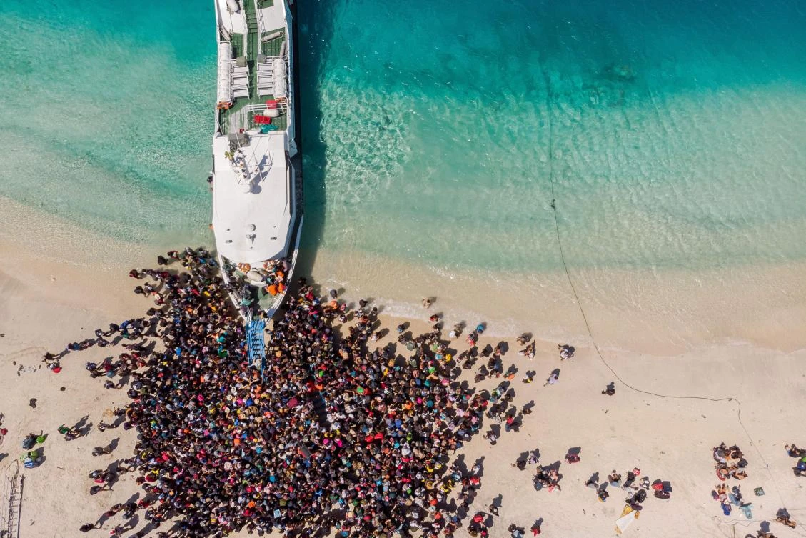 People crowd the beach as they wait to be evacuated from Gili Trawangan island to neighboring Lombok island a day after a 6.9 magnitude earthquake struck the area. (AFP/@trufflejournal/Melissa Delport)