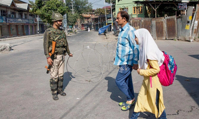 An Indian paramilitary soldier removes a barbed wire to make way for a Kashmiri man and his daughter during a strike called by separatists in Srinagar, Indian controlled Kashmir, Friday, Aug. 31, 2018. (AP)