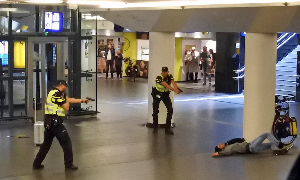 Dutch police officers point their guns at a wounded 19-year-old man who was shot by police after stabbing two people in the central railway station in Amsterdam, the Netherlands, Friday Aug. 31, 2018. (AP)