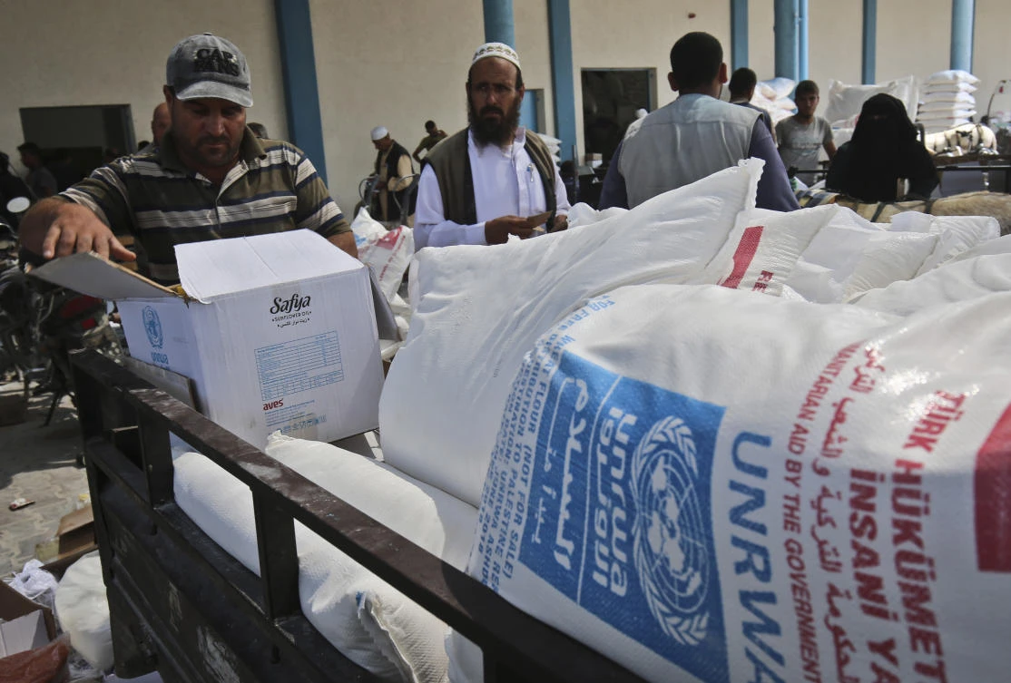 Palestinian men collect aid food at a United Nations’ compound in the Rafah refugee camp in the southern Gaza Strip on September 1, 2018. (AFP)