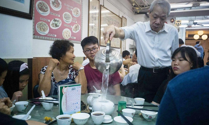 In this photo taken on August 7, 2018, a waiter pours freshly boiled water into a tea pot for diners eating dim sum at the Lin Heung Tea House in Hong Kong.(AFP)
