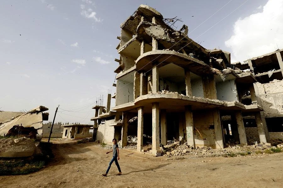 A Syrian man walks past destroyed buildings in Kobane on May 27, 2018. (File/AFP)