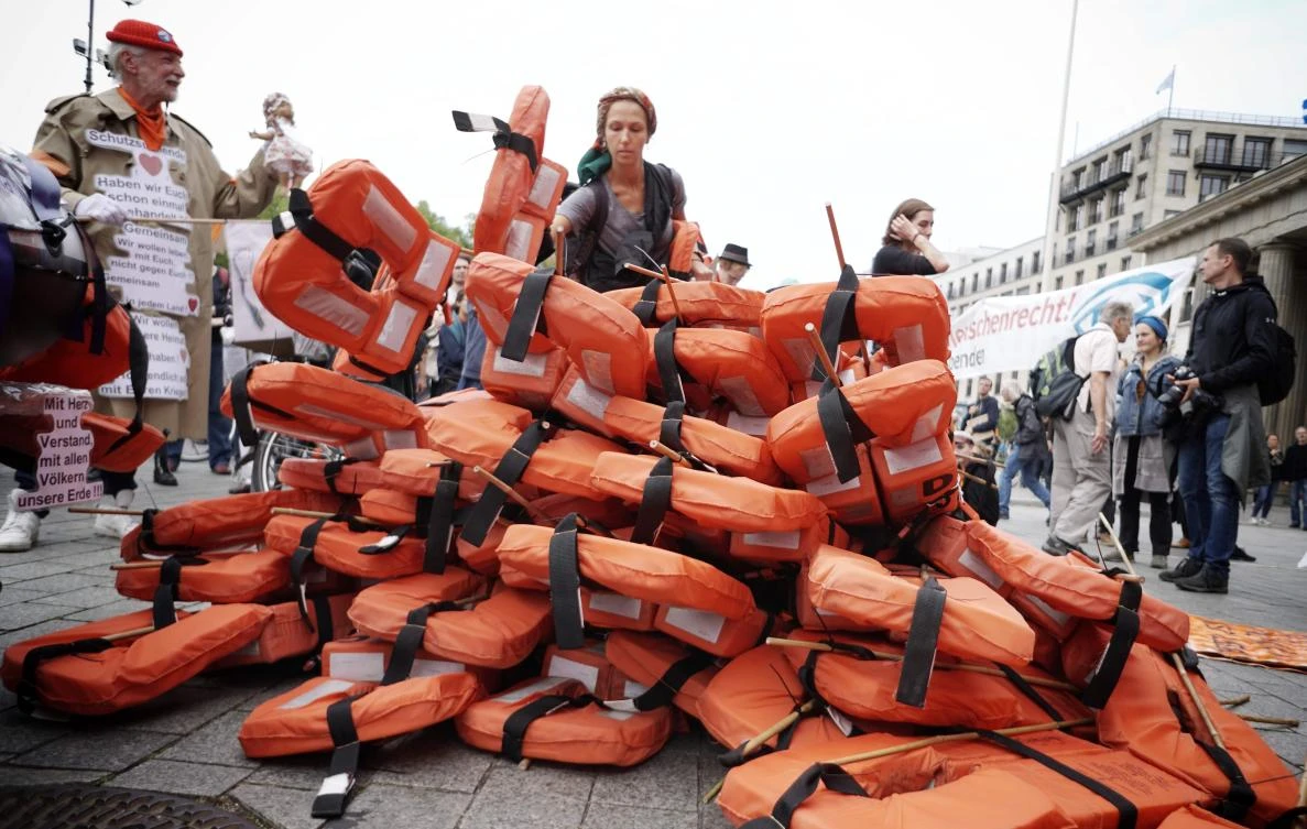 Supporters of the Seebruecke (sea bridge) movement pile up life vests during a demonstration for unhampered sea rescue of refugees in the Mediterranean Sea and for secure escape routes for migrants that was titled "Seebruecke creates safe harbours" on September 2, 2018 in front of the Brandenburg Gate in Berlin, Germany. (AFP)