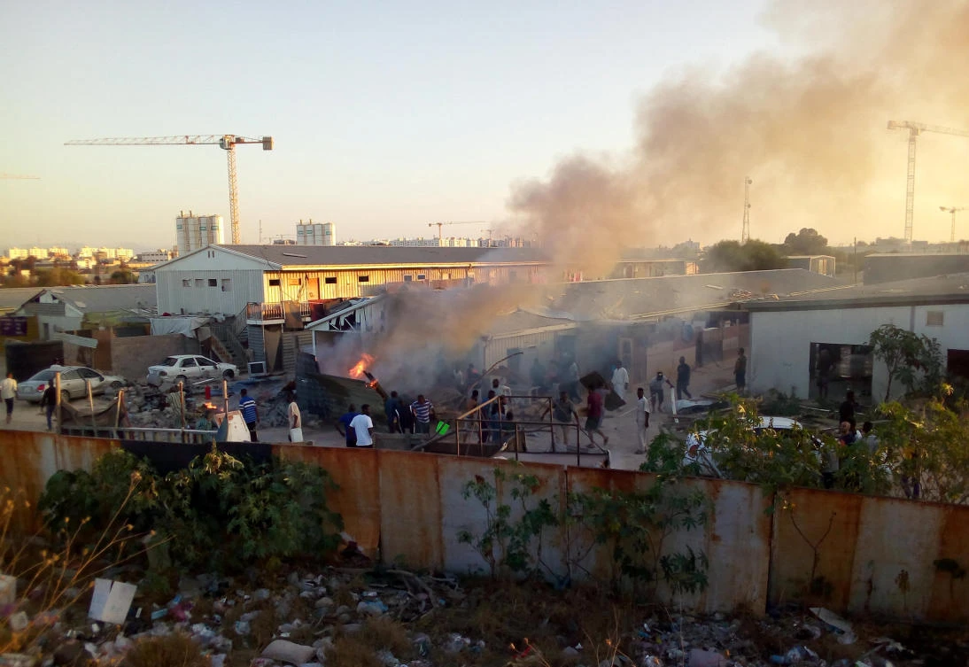 Smoke rises as people check the damage after a rocket hit a camp for displaced people during the fight between rival armed groups in Tripoli, Libya. (Reuters)