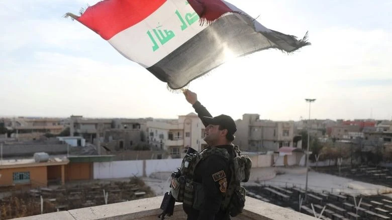 An Iraqi soldier waves an Iraqi flag from the top of a church damaged by ISIS fighters in Bartella, east of Mosul, Iraq. (Reuters)
