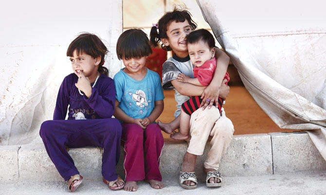 Children sit in the shade of a tent at a camp for the displaced in the Syrian province of Idlib. (AFP)