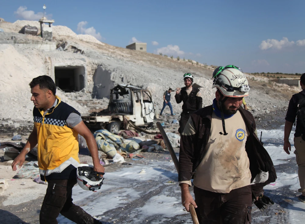 Syrian civil defense members search near a burned vehicle and personal belongings at a site in Hass town after an airstrike by pro-regime forces on the south of Idlib province on September 8, 2018. (AFP / Amer AlHamwe)
