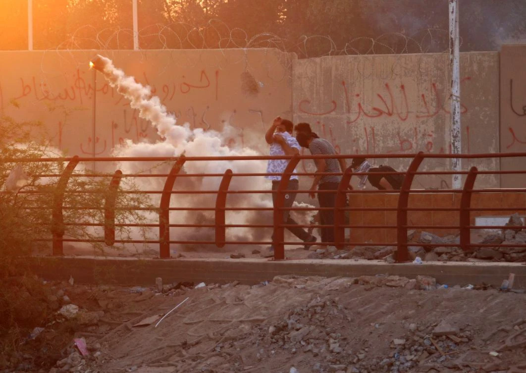 An Iraqi protester throws a tear gas canister toward the security forces who fired it during a protest against the government and the lack of basic services in the southern city of Basra. (File/AFP)