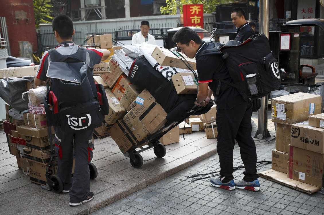 Delivery workers pull carts loaded boxes of goods for their customers outside an office building in Beijing, Monday, Sept. 10, 2018. (AP)