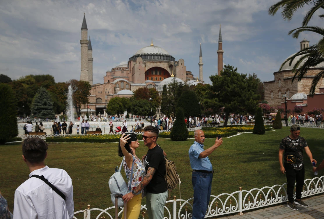 In this Friday, Aug. 17, 2018 file photo, backdropped by the Byzantine-era Hagia Sophia, one of Istanbul's main tourist attractions, tourists enjoy the plaza in the historic Sultanahmet district of Istanbul. (AP)