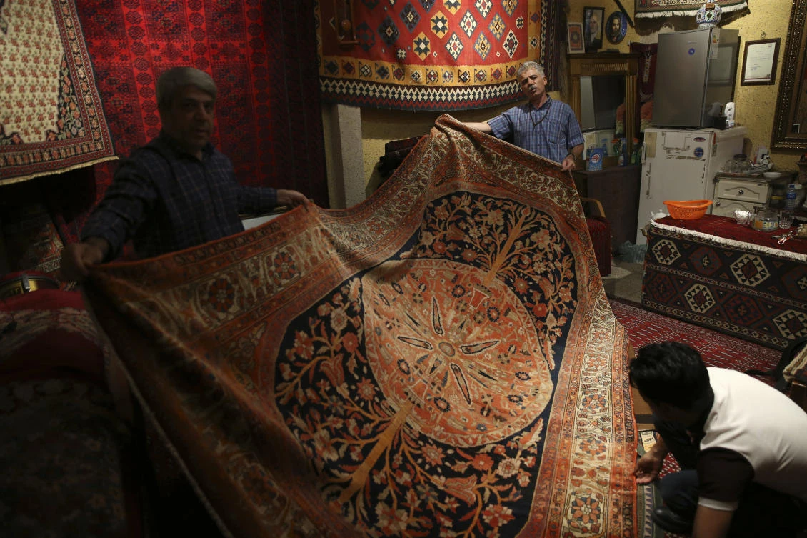 Merchants display an old carpet in a shop at the Grand Bazaar in Tehran. (AP)