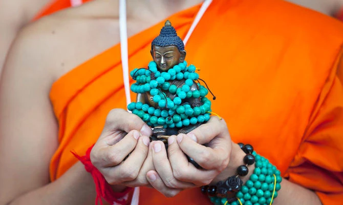 A Thai Buddhist monk carries a statue of Buddha as he waits with others to welcome Tibetan spiritual leader Dalai Lama at the Tsuglagkhang temple in Dharmsala, India, Friday, Sept. 7, 2018. (AP)