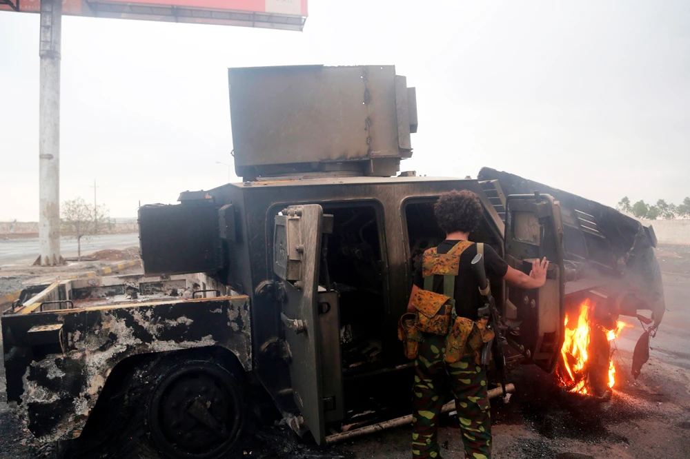 A Houthi rebel inspects a burnt armored vehicle on September 13, 2018, reportedly destroyed in an air strike during clashes with Coalition-backed forces of Yemen President Abed Rabbo Mansour Hadi near the eastern entrance of the Yemeni city of Hodeidah. (AFP)
