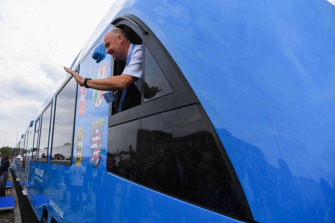 An employee of French train maker Alstom, waves from a window upon the arrival of Alstom's first hydrogen-powered train at the train station in Bremervoerde, Germany as it enters service on September 16, 2018. (AFP)