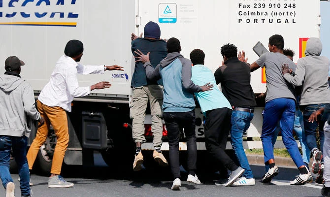 Migrants attempt to open the rear door of a truck at the Brittany ferry port in Ouistreham, northwestern France, on September 18, 2018. (AFP)
