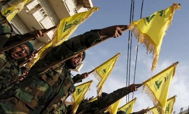 Members of Lebanon’s Iranian-backed Hezbollah group carry Hezbollah flags in southern Lebanon. (Reuters/File Photo)