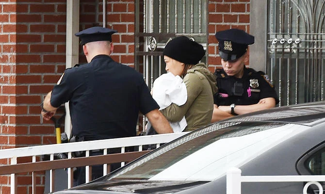 A woman is escorted by police out of a daycare center, Mei Xin Care Incorporated located at the owner’s home in the Flushing area of Queens, September 21, 2018 after a female attacker stabbed five people, including three children. (AFP)