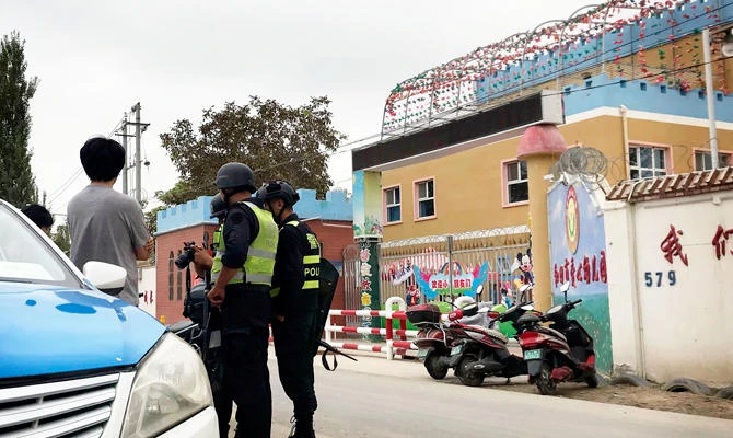 In this Aug. 30, 2018, photo, security personnel inspect camera equipment of journalists outside the Hotel City Kindness Kindergarten, where Meripet learnt her children are kept in Hotan, in western China's Xinjiang region. (AP)