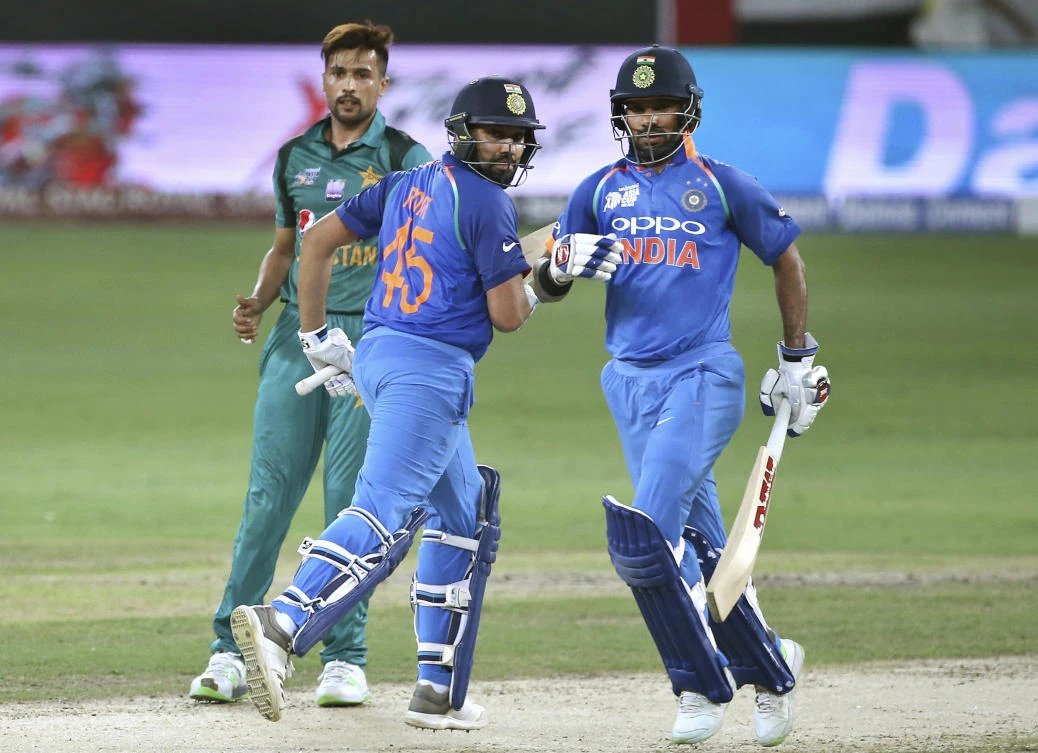 Pakistan's Mohammad Amir, left, looks on as India's Shikhar Dhawan, right, and captain Rohit Sharma run between the wickets during the Asia Cup ODI in Dubai. (AP)