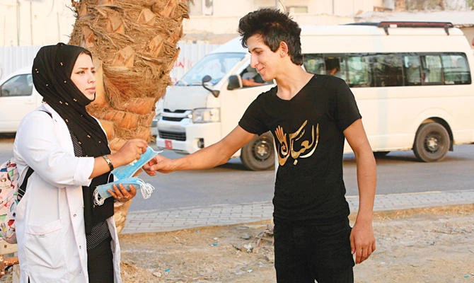 Iraqi activist Hajjar Youssif hands out masks to protesters for a demonstration last week in Basra. (AP)