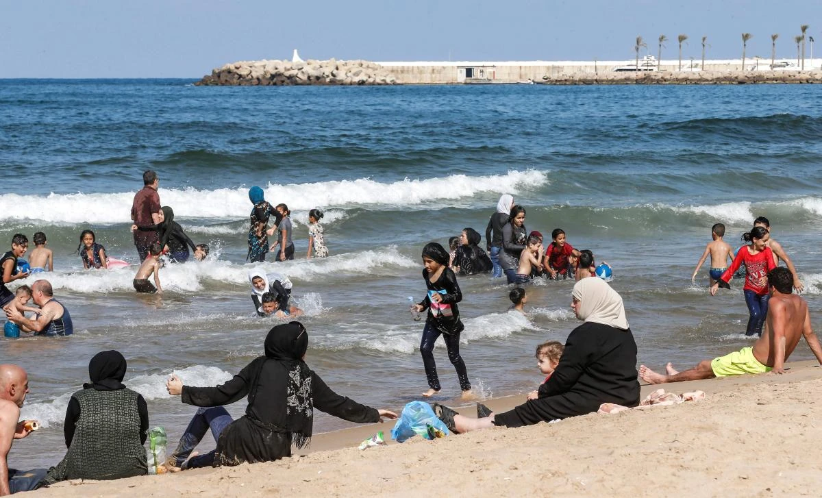 Syrian refugees sit and swim at a public beach in the Lebanese capital Beirut's Ramlet al-Baida neighbourhood on September 15, 2018. (AFP)