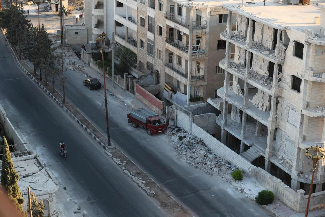 A motorcyclist drives past damage buildings in the rebel-held northern Syrian city of Idlib on September 23, 2018. (AFP)