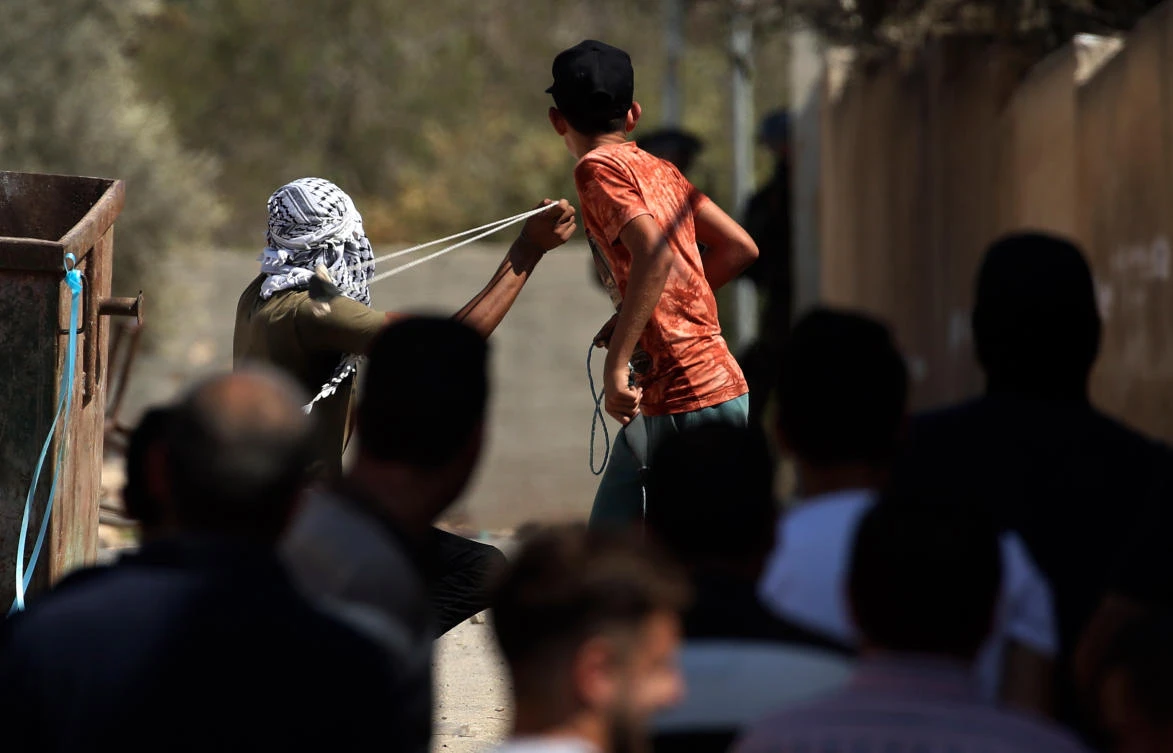 A Palestinian protester hurls a rock at Israeli soldiers during clashes following a weekly demonstration against the expropriation of Palestinian lands in the village of Kfar Qaddum, near Nablus in the occupied West Bank, on September 21, 2018. (AFP)