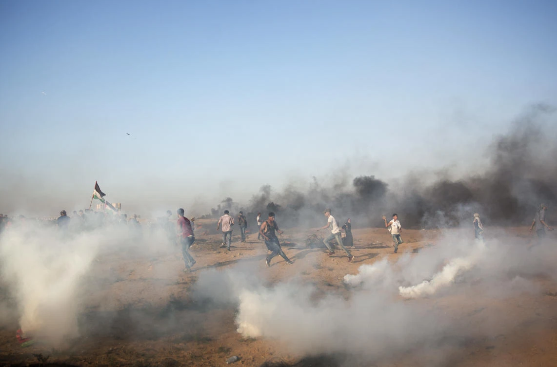Palestinian protesters run for cover from teargas fired by Israeli troops during a protest at the Gaza Strip's border with Israel, Friday, Sept.28, 2018. (AP)