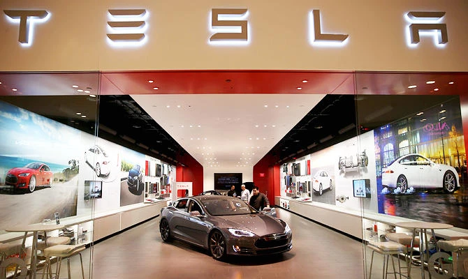 In this file photo taken on February 18, 2014, people look at a Tesla Motors vehicle on the showroom floor at the Dadeland Mall in Miami, Florida. (AFP)
