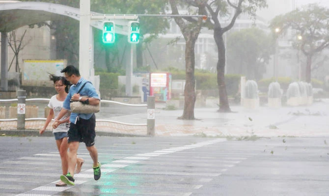A couple crosses the street in the city centre of Naha, Okinawa prefecture, on September 29, 2018 as typhoon Trami is actually hitting Japan. (AFP)