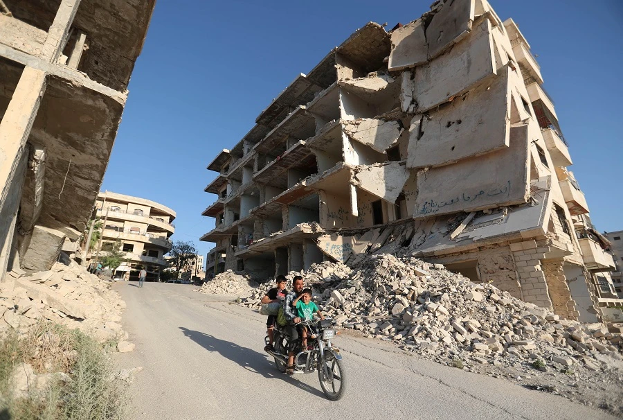 Syrian men ride a motorcycle past heavily-damaged buildings in the rebel-held town of Maaret al-Numan, in the north of Idlib province on September 27, 2018. (AFP)