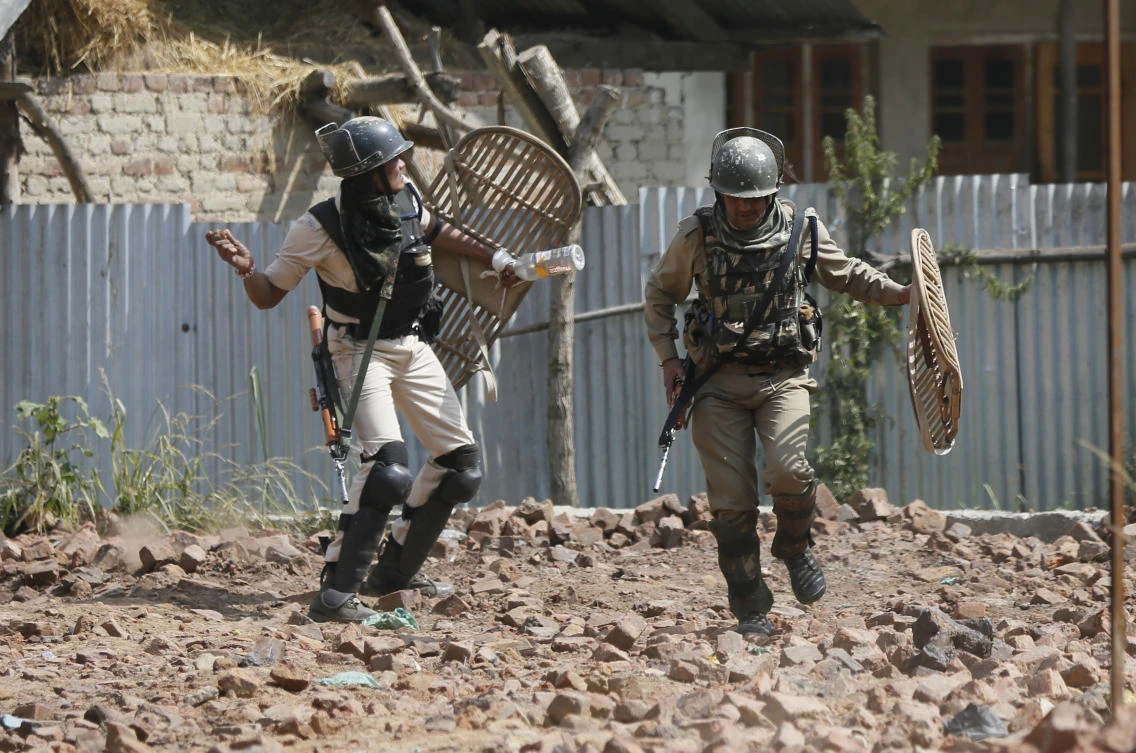 Indian paramilitary soldiers clash with Kashmiri protesters during a protest near the site of a gunbattle at Panzan, about 35 kilometers south of Srinagar, Indian controlled Kashmir, Thursday, Sept. 27, 2018. At least two militants were trapped in a mosque after troops laid a siege around it in the village, police said. As the siege continued, villagers tried to march towards the mosque in solidarity with the rebels, leading to clashes between stone-throwing protesters and government forces who deployed tear smoke shells and pellets. (AP Photo/Mukhtar Khan)