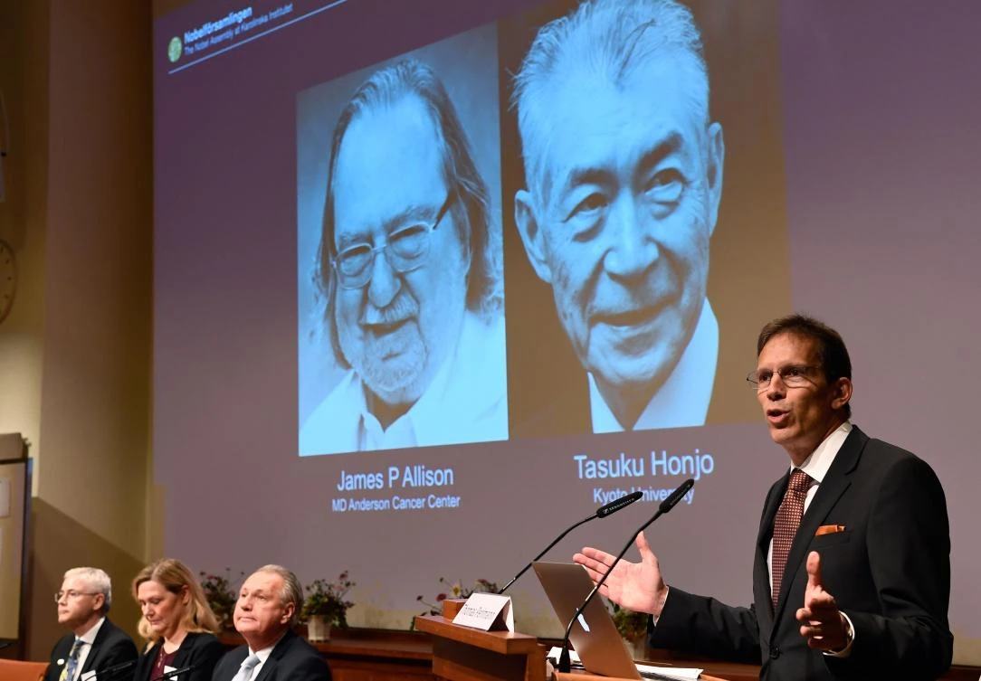 Secretary of the Nobel Committee for Physiology or Medicine Thomas Perlmann, right, stands next to a screen displaying portraits of James P Allison, left, and Tasuku Honjo during the announcement of the winners of the 2018 Nobel Prize in Physiology or Medicine on Monday, October 1. (AFP)