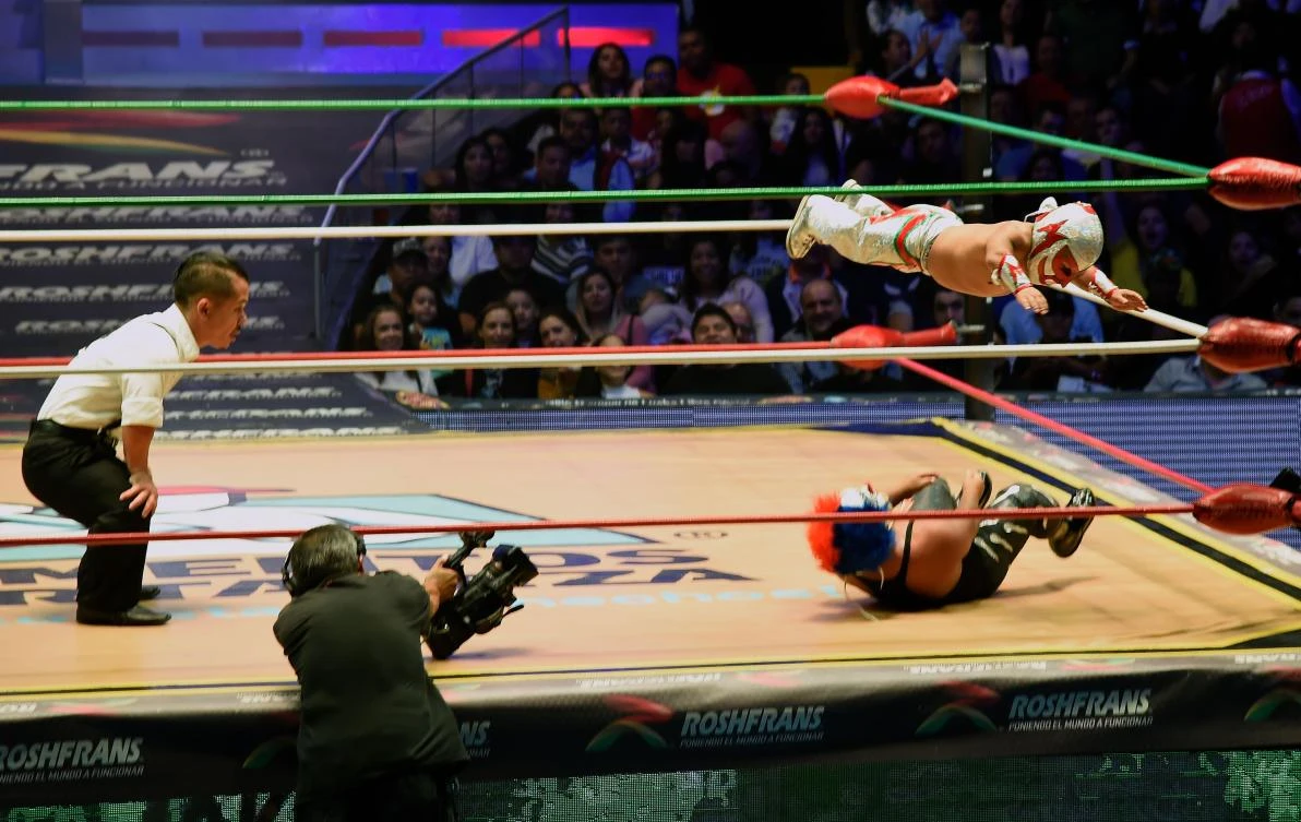 Mexican dwarf fighter Microman jumps on his opponent during a fight at the Arena Mexico, in Mexico City on September 07, 2018. "Microstars" is a show that mixes sport, circus and collective catharsis in what Mexicans call "fights". / AFP / ALFREDO ESTRELLA