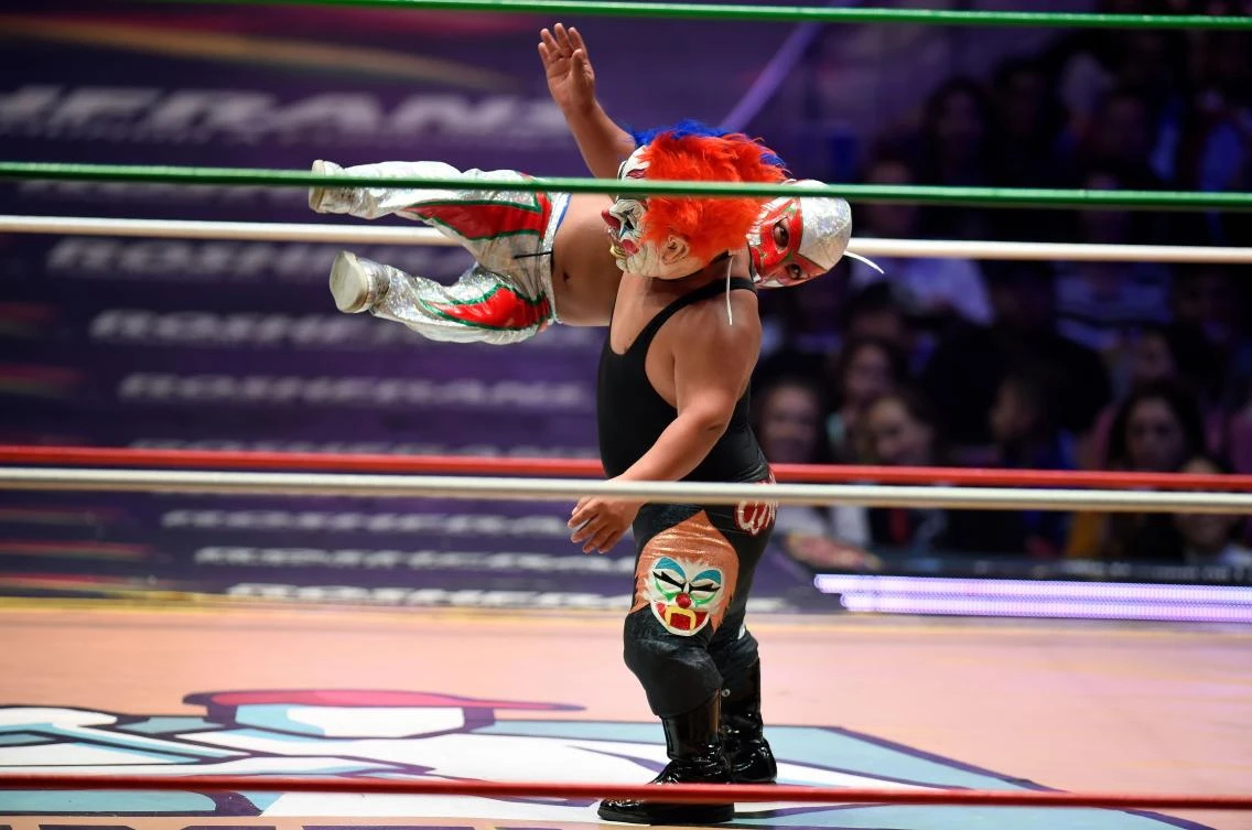Mexican dwarf fighter Microman (red) struggles with his opponent during a fight at the Arena Mexico, in Mexico City on September 07, 2018. "Microstars" is a show that mixes sport, circus and collective catharsis in what Mexicans call "fights". / AFP / ALFREDO ESTRELLA