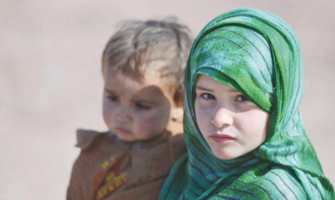 An Afghan refugee girl carries her brother at a refugee camp on the outskirts of Islamabad on Feb. 1, 2018. (AFP)