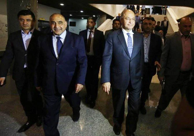 President Barham Salih, right, walks out of the Iraqi parliament with prime minister designate Adel Abdul Mahdi, second left, on Tuesday, October 2. (AFP)