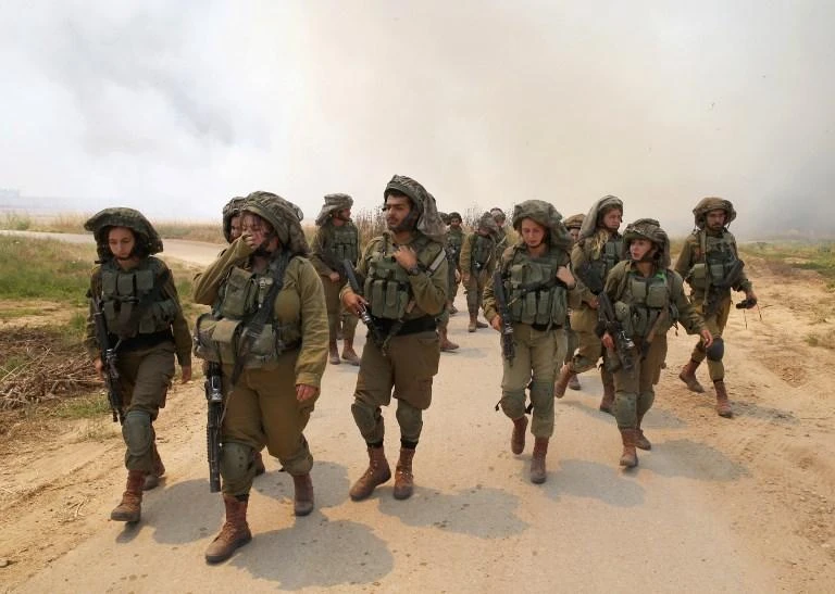 Israeli soldiers walk amidst smoke from a fire in a wheat field near the Kibbutz of Nahal Oz, along the border with the Gaza Strip, on May 14. (AFP)