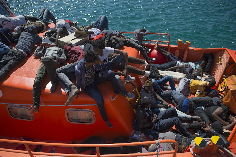 Migrants wait to be transferred after arriving aboard a coast guard boat. (File photo / AFP)