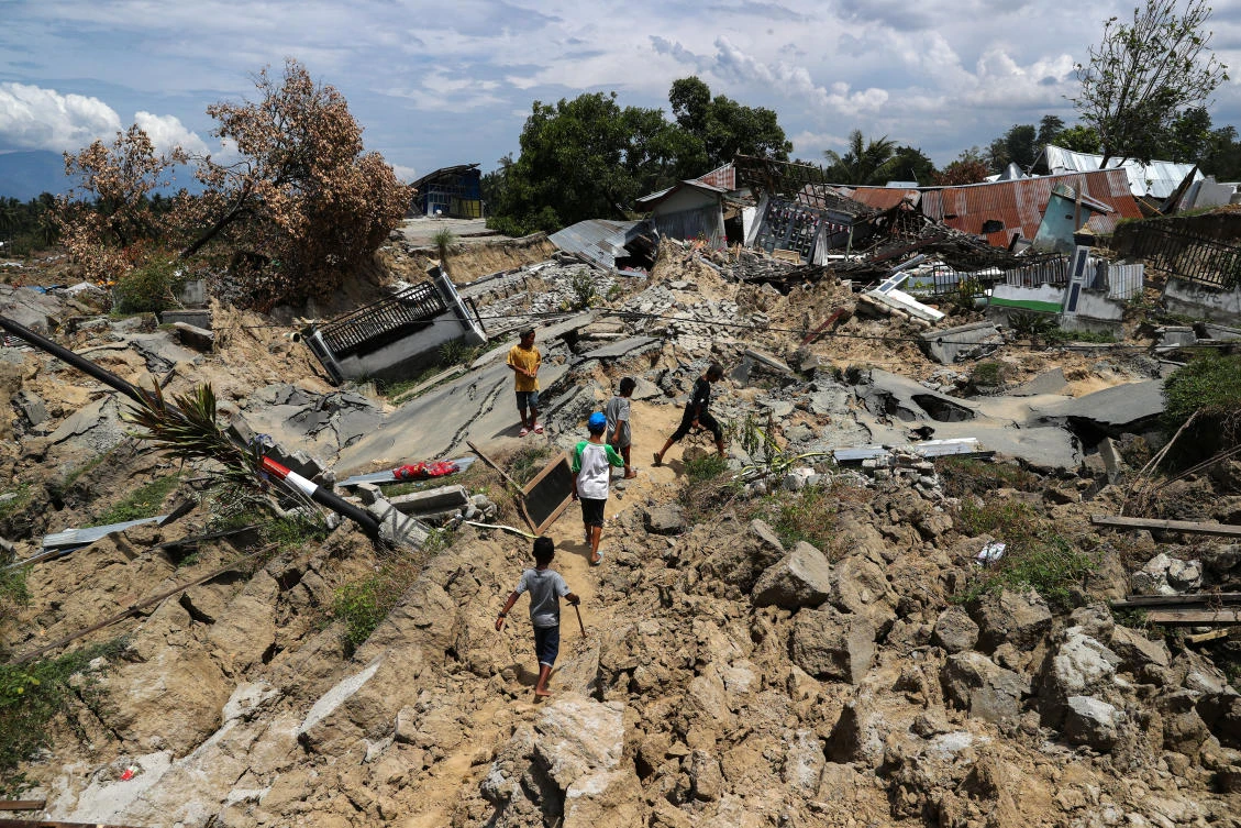 Children walk past a damaged area hit by a 7.5 magnitude earthquake hit in Palu, Indonesia. (Reuters)